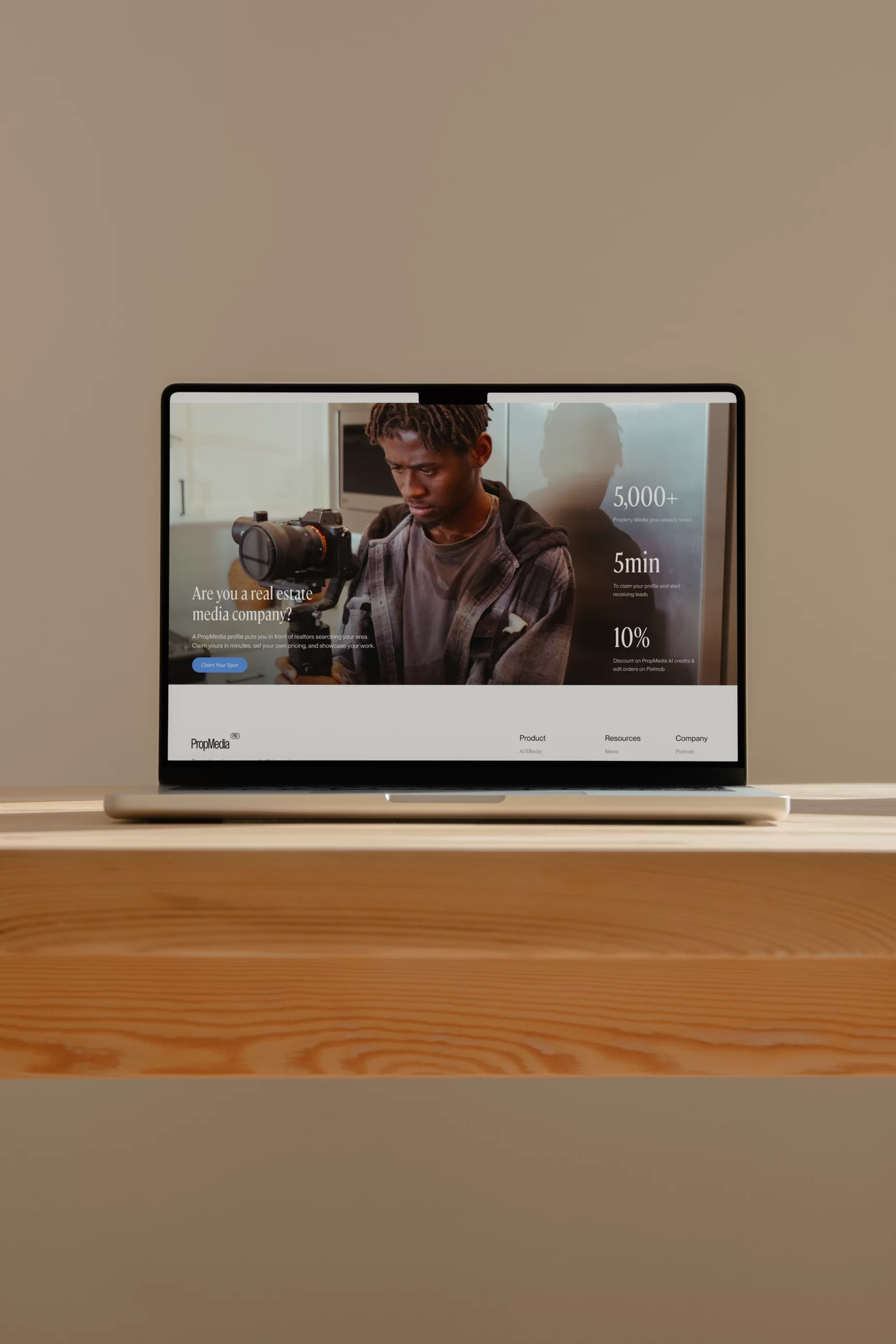 Laptop on a wooden desk showing PropMedia’s “Are you a real estate media company?” page
